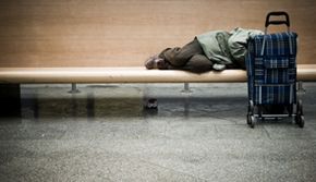Menschen in besonderen Lebenslagen - Das Bild zeigt einen auf einer Bank schlafenden Obdachlosen